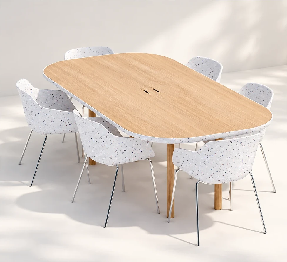 Table de réunion au plateau de chêne aux angles arrondis, cerclée d'un pourtour blanc moucheté de bleu et de rouge, sur pieds cylindriques en bois, entourée de six chaises coques assorties aux pieds chromés.